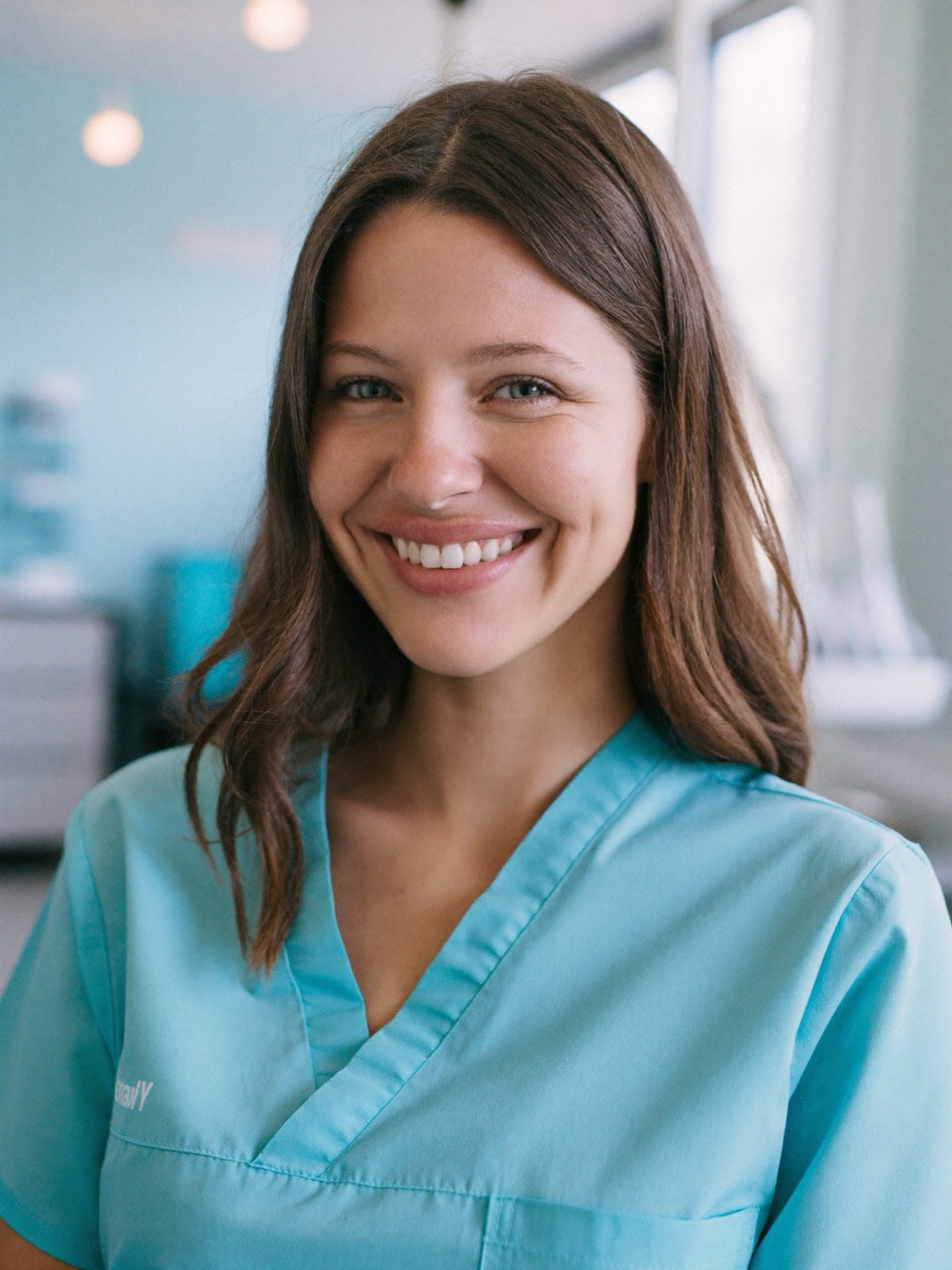 Leah Kowalski, dental hygienist, smiling in light blue scrubs