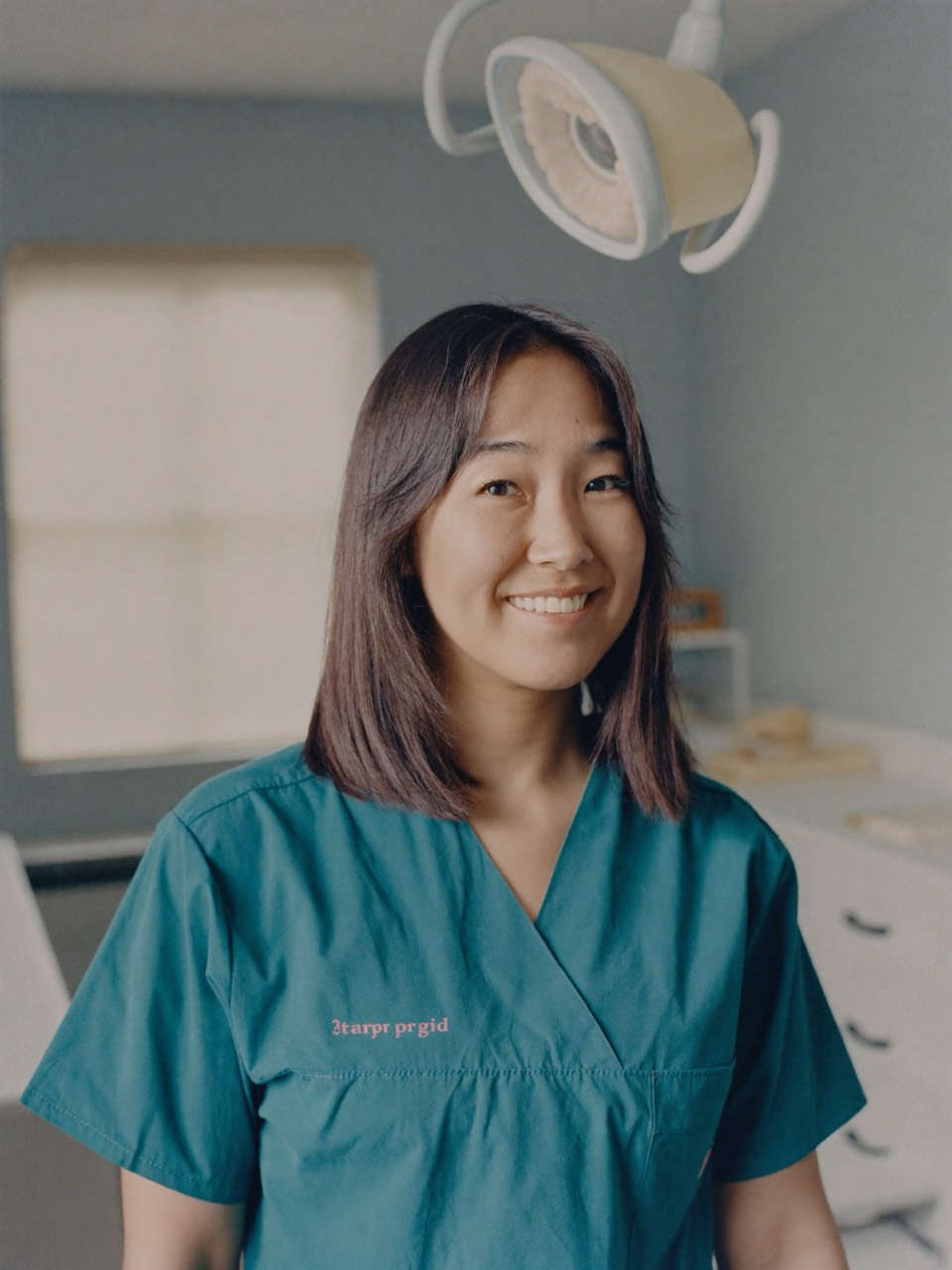 Dr. Maya Tran smiling in teal scrubs in a treatment room